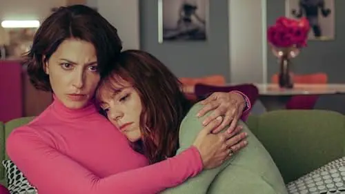 A woman in a pink turtleneck hugs another woman in a green sweater, who leans her head against the first woman’s shoulder at the Austin Film Festival 2026.
