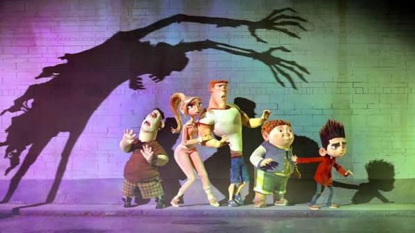 Four Laika Studios characters look in fear at a large, monstrous shadow cast on a brick wall.