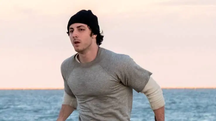 A man wearing a beanie and a gray shirt runs along the shore at AFI FEST 2026.