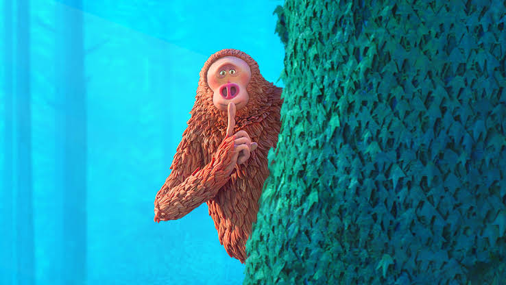 A claymation orangutan in the style of Laika films peeks from behind a tree, holding a finger to its lips in a shushing gesture.